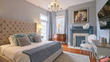 Um quarto com uma cama grande, um lustre, uma lareira e um quadro na parede.