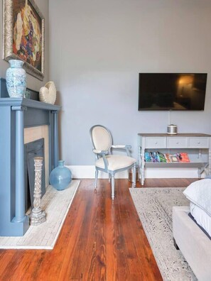 Ein Zimmer mit Kamin, Sessel, Fernseher und Bücherregal.