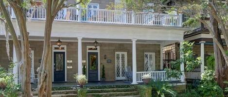 A two-story house with a front porch, steps, and a small garden.