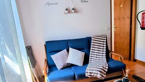 Ein gemütliches Wohnzimmer mit einem blauen Sofa, einem Holztisch und einer kleinen Pflanze.