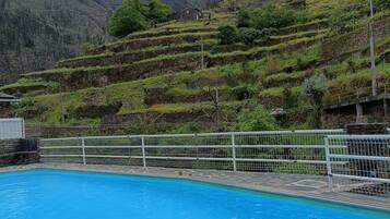 Una piscina con una recinzione bianca e un paesaggio collinare sullo sfondo.