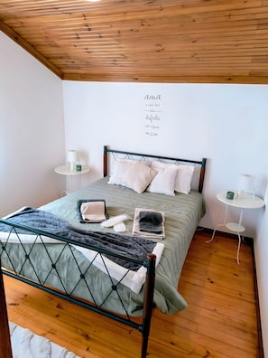 Une chambre à coucher bien rangée, avec un lit, des tables de chevet et un mur orné d’une citation inspirante.