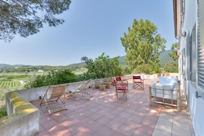 Eine Terrasse mit Gartenmöbeln, Blumentöpfen und Blick auf die Landschaft.
