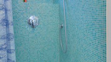 Eine Dusche mit Duschbrause, Wandarmatur und kleinem Fenster darüber.