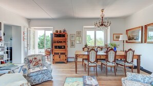 Ein geräumiges Wohnzimmer mit Essbereich, Holzmöbeln und einer Kristallleuchtre.