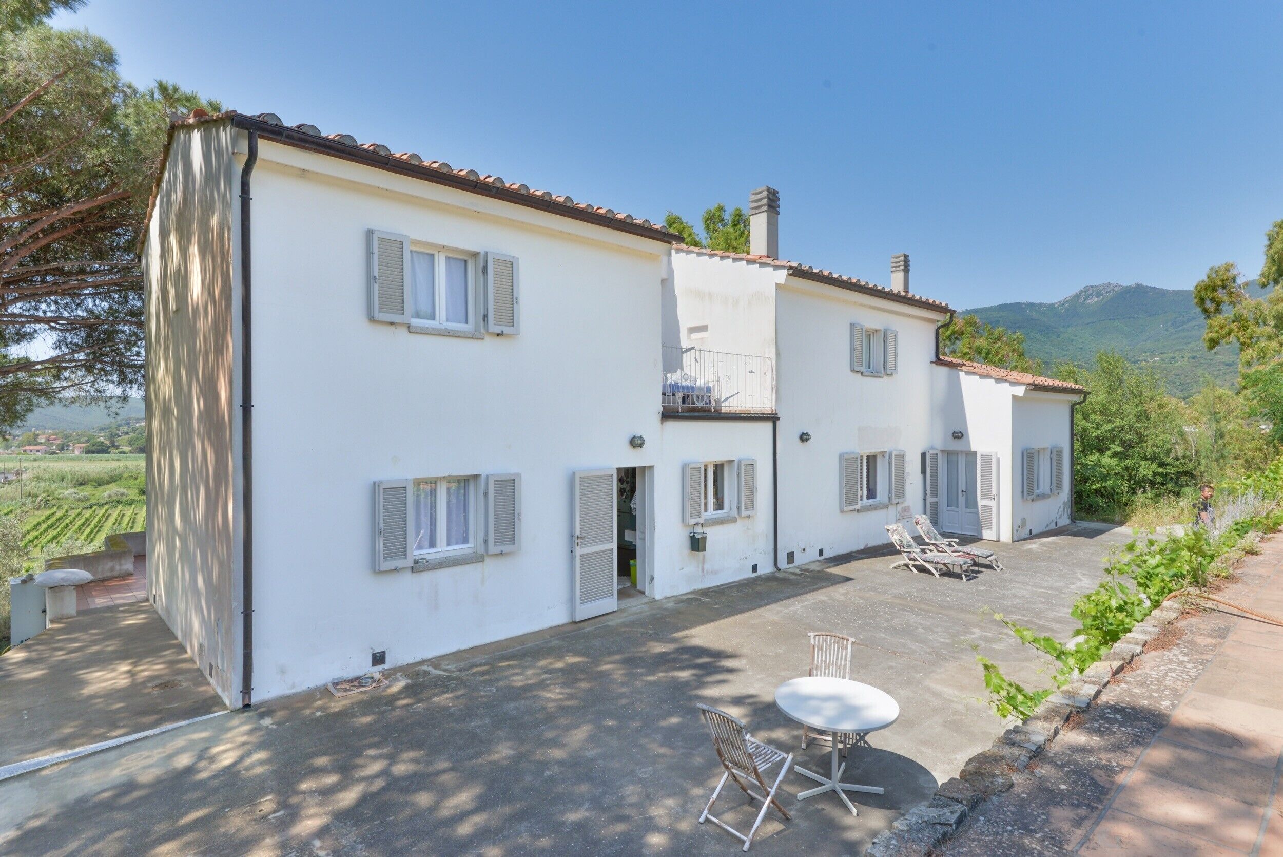 Une maison à deux étages dotée d’une terrasse, d’un espace salon extérieur et offrant une vue sur la campagne.