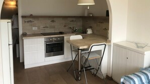 A compact kitchen with a built-in oven, a sink, and a small dining area with a chair. - Holiday Home 'Terrazza sul Mare' with Sea View and Private Terrace (Marina di Campo)