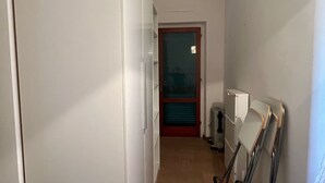 A narrow hallway with a white door at the end, a radiator, and a white cabinet. - Holiday Home 'Terrazza sul Mare' with Sea View and Private Terrace (Marina di Campo)