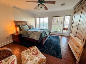 A bedroom with a bed, a nightstand, a dresser, a ceiling fan, and a window with blinds. - The Idlewylde Retreat: Woodland Charm, Mountain Views, & Hot Tub (Morrilton)