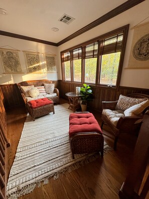 A cozy room with a large window, wicker furniture, and a woven rug. - The Idlewylde Retreat: Woodland Charm, Mountain Views, & Hot Tub (Morrilton)