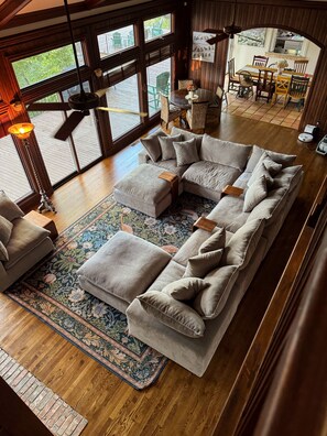 A spacious living area with a large sectional sofa, a coffee table, and a patterned rug. - The Idlewylde Retreat: Woodland Charm, Mountain Views, & Hot Tub (Morrilton)