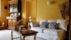 Una sala de estar con un sofá, una mesa de centro, un aparador con puertas de vidrio y una lámpara.