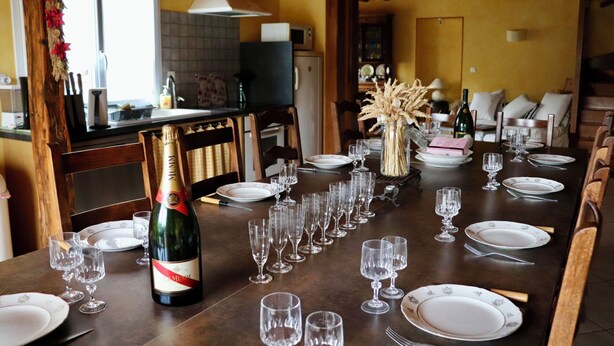 Una mesa de comedor preparada para una comida, con copas de vino, platos y una botella de champán.