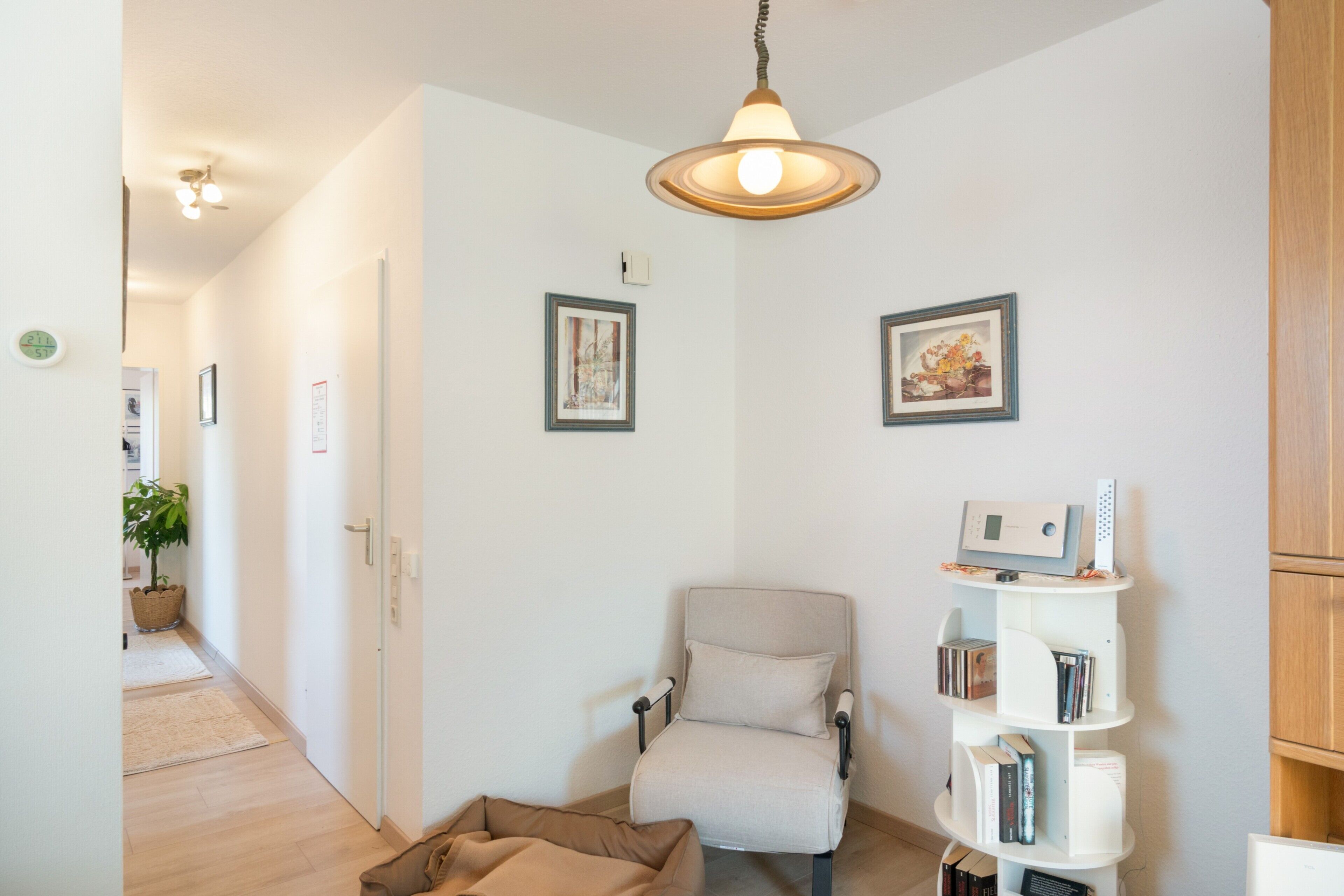 Een moderne woonkamer met een bank, een klein boekenrek en een decoratieve lamp.