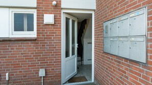 Een bakstenen gebouw met een deur die uitkomt op een wenteltrap en een rij metalen kasten aan de rechterkant.