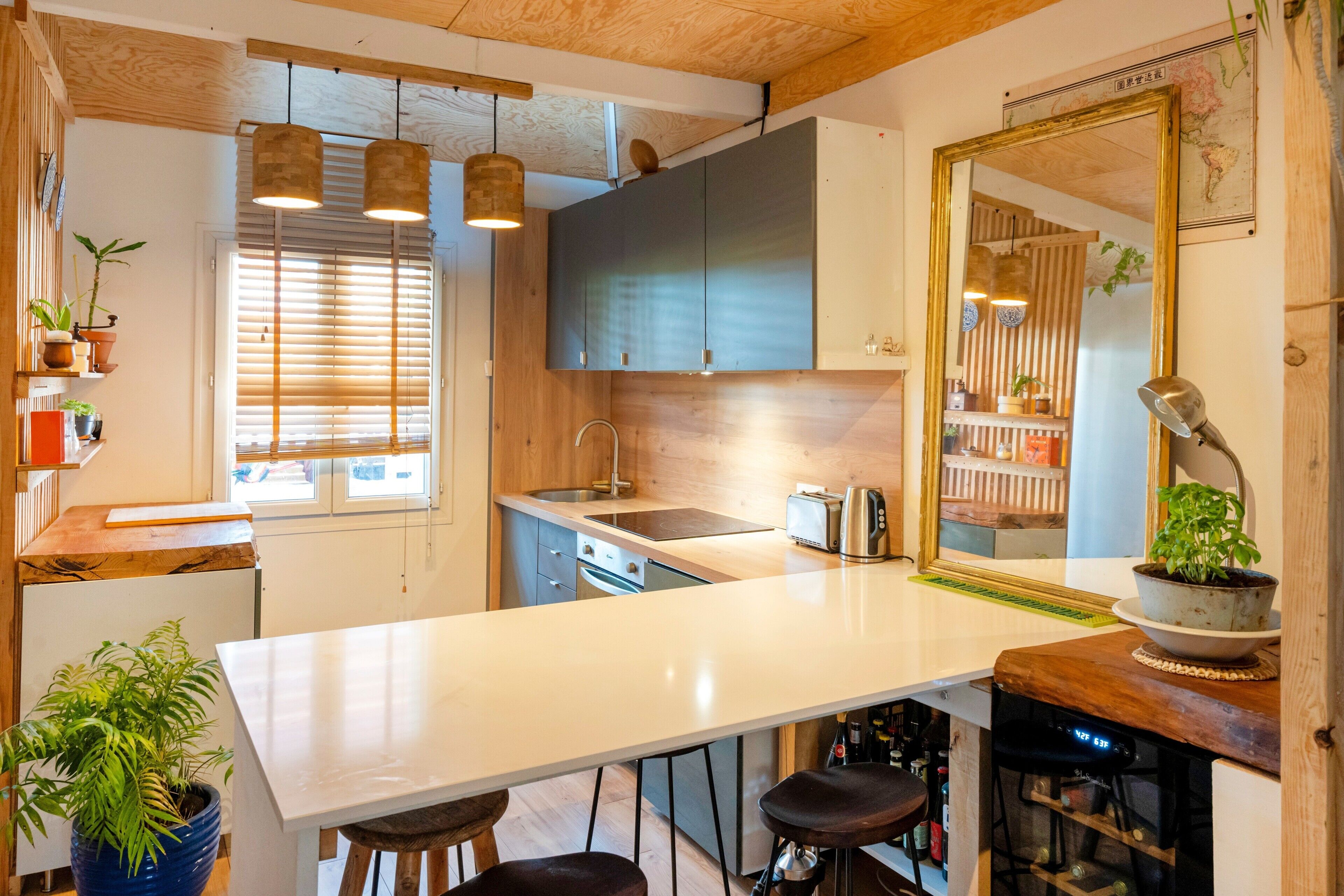 A modern kitchen with a large island, wooden ceiling, and pendant lighting.