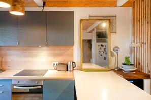 A modern kitchen with a wooden countertop, a toaster, a kettle, and a large mirror. - Stay in the Heart of Capbreton with Private Terrace (Capbreton)