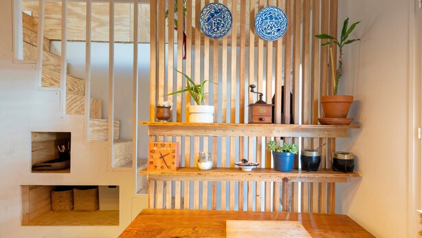 Ein modernes Interieur mit einem Holztisch, Regalen mit Dekoration und einer Uhr.