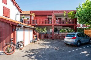 A multi-story building with balconies, a bicycle, and a parked car. - Stay in the Heart of Capbreton with Private Terrace (Capbreton)