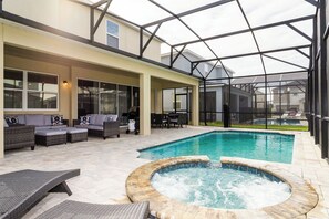 Uma área externa coberta com piscina, ofurô e espaço para sentar.