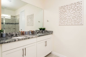 A bathroom with a marble countertop, two sinks, a large mirror, and decorative wall panels. - Modern 9BR Family Villa Pool and Relax (Kissimmee)