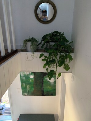 A staircase with a potted plant, a mirror, and a green wall painting. - THE HOUSE NEXT DOOR TO STRASBOURG (Illkirch-Graffenstaden)