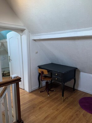 Ein Zimmer mit Schreibtisch, Stuhl, Holzboden und einem violetten Teppich.