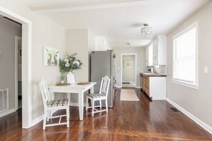 Eine moderne Küche mit Essbereich, Holzboden, weißen Schränken und einem Kühlschrank.
