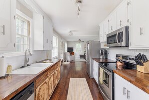 Eine Küche mit weißen Schränken, Edelstahlgeräten und einer Holzausziehtafel.