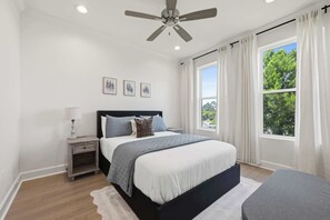 A bedroom with a bed, nightstand, ceiling fan, and a large window with curtains. - Kali House •  River Ranch • Prime Location • Premier Host (Lafayette)