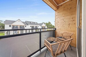 A balcony with wicker chairs and a table, overlooking a residential area. - Kali House •  River Ranch • Prime Location • Premier Host (Lafayette)
