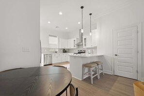 A modern kitchen with white cabinets, a central island, and pendant lighting. - Kali House •  River Ranch • Prime Location • Premier Host (Lafayette)