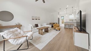 Ein modernes Wohnzimmer mit Sofa, Sessel, Couchtisch und Fernseher.