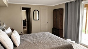 A bedroom with a bed, a wardrobe, a mirror, and a door leading to another room.