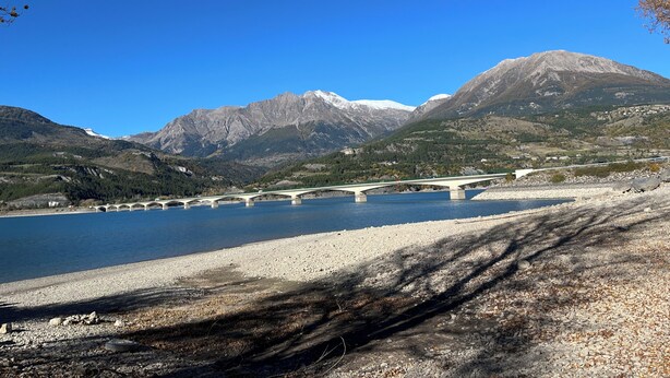 Un pont enjambant une rivière, avec des montagnes en arrière-plan.