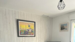 Ein Wohnzimmer mit einer Couch, einem Sessel, einem Fernseher und einem Bild an der Wand.