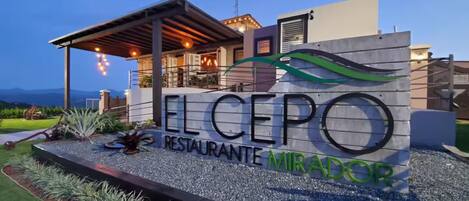 A sign for 'ELCEPO RESTAURANTE MIRADOR' with a modern building in the background.
