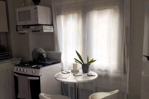 Keittiössä on liesi, mikroaaltouuni sekä pieni pöytä, jonka päällä on kasvi ja kynttilä.