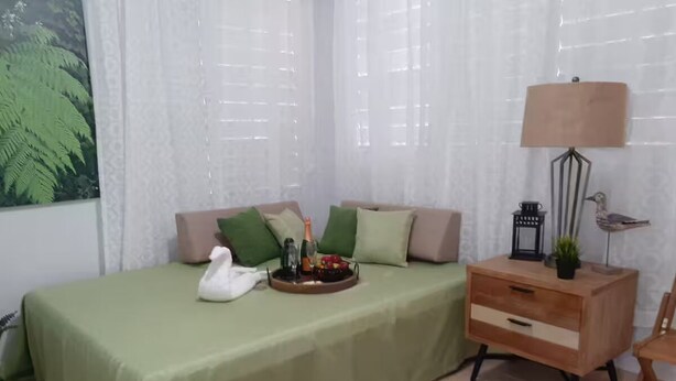 Un dormitorio ordenado con cama, mesita de noche, lámpara y un cuadro enmarcado.