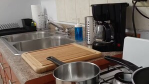 Una cocina con estufa, pileta y diversos utensilios.