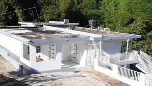 Un edificio moderno con techo plano, varias habitaciones y fachada blanca.