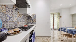 Una cocina con baldosas estampadas, una estufa y un comedor con mesa y sillas.