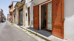 Una calle estrecha con edificios, puertas de madera y balcones.