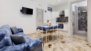 Una sala de estar con sofá, una mesa de comedor y una cocina con salpicadero de azulejos.
