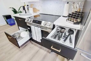 A compact kitchen with a built-in stove, a sink, and a drawer with utensils. - 5 Bedroom Island House perfect for large groups (Port Colborne)