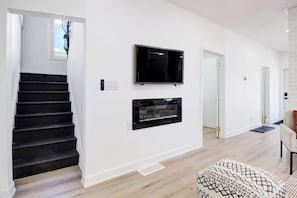 A modern interior with a staircase, a flat-screen TV, and a fireplace. - 5 Bedroom Island House perfect for large groups (Port Colborne)