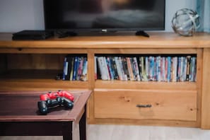 A wooden entertainment center with a television, video games, and a DVD collection. - Wylde Roots Escape - Hidden Beachside Cottage (Port Colborne)