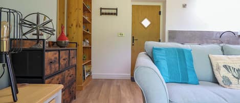 Una sala de estar con un sofá, un aparador de madera y una estantería.