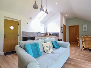 Una sala de estar acogedora con un sofá, un comedor con mesa y sillas, una cocina equipada y una puerta de madera.