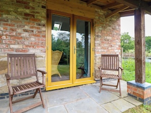 A brick building with a glass door and two wooden chairs outside.